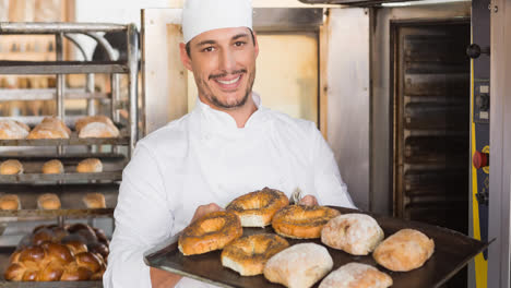 Lächelnder-Kaukasischer-Männlicher-Bäcker-Mit-Schürze,-Der-Brötchen-In-Einer-Professionellen-Bäckerei-Zubereitet