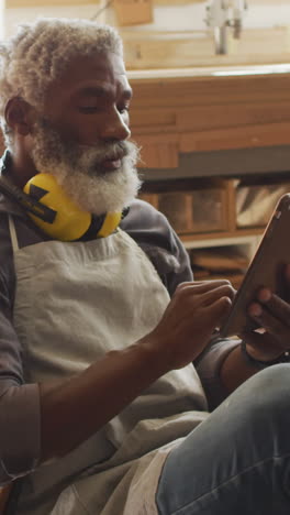 Artesano-Afroamericano-Revisa-Planes-En-Una-Tableta-En-Un-Taller