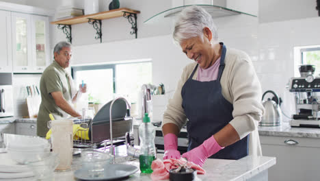 Happy-senior-biracial-couple-washing-dishes-in-kitchen