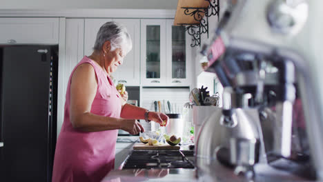 Happy-senior-biracial-couple-preparing-healthy-drink-in-kitchen