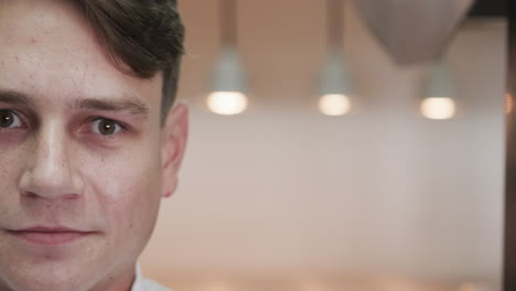 Half-portrait-of-happy-caucasian-male-chef-smiling-in-kitchen,-copy-space,-slow-motion