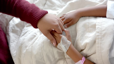 Holding-hands-of-african-american-mother-and-daughter-lying-in-hospital-bed,-slow-motion