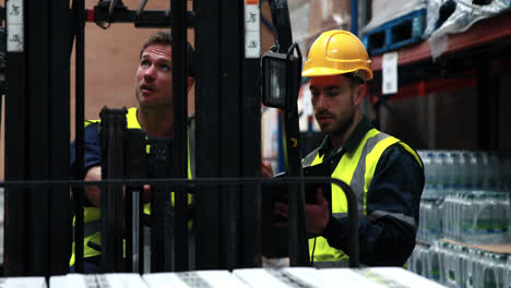 Warehouse-worker-talking-with-forklift-driver-