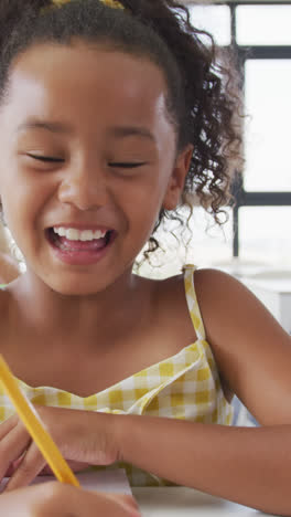 Video-of-happy-biracial-girl-sitting-at-school-desk-and-learning