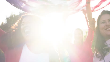 Happy-diverse-male-and-female-friends-dancing-with-flags-in-sunny-garden