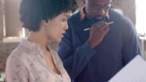 Un-Joven-Afroamericano-Y-Una-Mujer-Revisan-Documentos-Comerciales-En-Un-Ambiente-De-Oficina