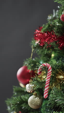 Vertical-video-of-christmas-tree-with-candy-cane-and-decorations-and-copy-space-on-black-background