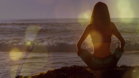 Animación-De-Luces-Sobre-La-Vista-Trasera-De-Una-Mujer-Caucásica-Practicando-Yoga-En-La-Playa