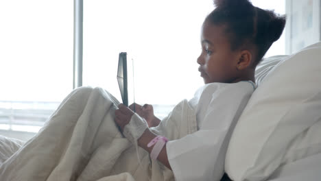 African-american-girl-using-tablet-in-hospital-bed,-slow-motion