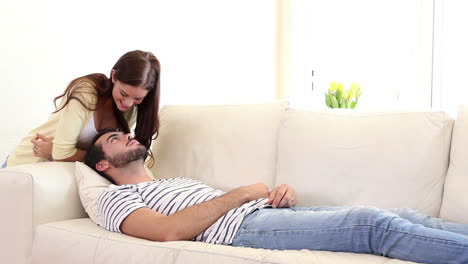 Handsome-man-sleeping-on-couch-being-woken-by-girlfriend