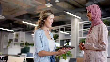 Happy-diverse-creative-female-colleagues-in-discussion-using-tablet-in-office,-slow-motion