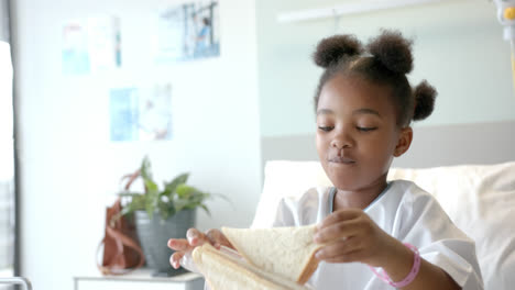 African-american-girl-eating-lunch-in-hospital-bed,-slow-motion