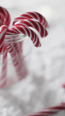 Vertikales-Video-Von-Weihnachtszuckerstangen-Im-Glasgefäß-Und-Kopierraum-Auf-Schneehintergrund