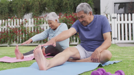 Happy-senior-diverse-couple-practicing-yoga-in-garden