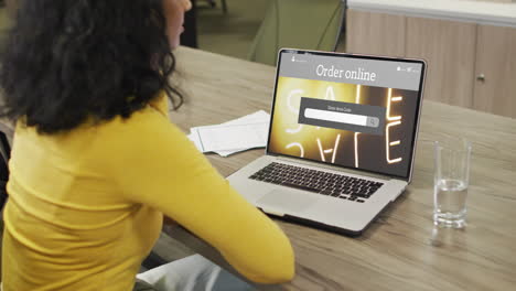 Biracial-woman-at-table-using-laptop,-online-shopping-during-sale,-slow-motion