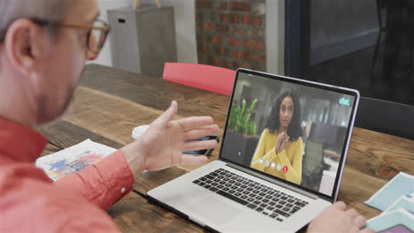 Caucasian-businessman-on-laptop-video-call-with-african-american-female-colleague-on-screen