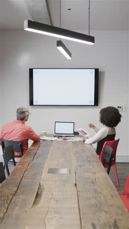 Vertical-video-of-diverse-male-and-female-colleague-in-casual-office-having-video-call,-copy-space