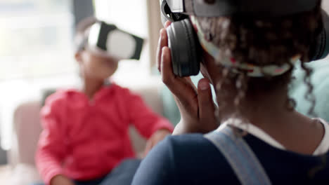 African-american-sister-and-brother-using-vr-headset-in-living-room,-slow-motion