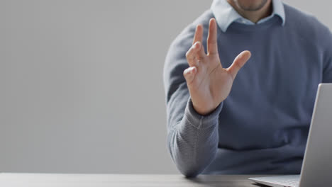 Midsection-of-biracial-businessman-using-laptop-and-holographic-display,-with-copy-space