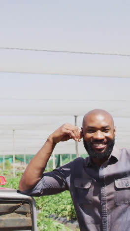 Video-of-happy-african-american-man-standing-in-front-of-tractor