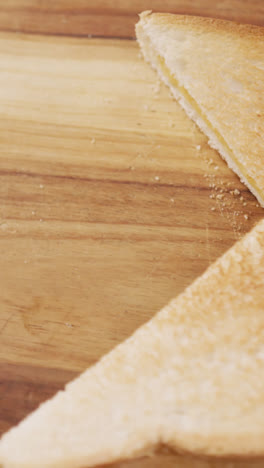 Video-of-slices-of-toasted-cheese-white-bread-sandwiches-on-wooden-chopping-board-background