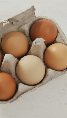 Video-of-overhead-view-of-brown-eggs-in-egg-carton-on-rustic-background