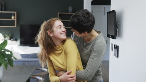 Feliz-Pareja-De-Lesbianas-Caucásicas-Abrazándose,-Sonriendo-Y-Riendo-En-La-Soleada-Cocina