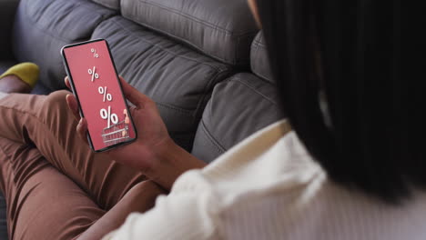 Biracial-woman-on-couch-using-smartphone-for-online-shopping,-slow-motion