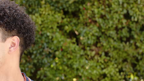 Biracial-man-smiling-in-front-of-hedge-outdoors,-slow-motion,-copy-space