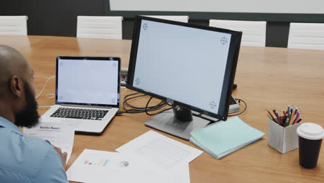 African-american-businessman-using-computer-and-laptop,-with-copy-space-on-screens,-slow-motion