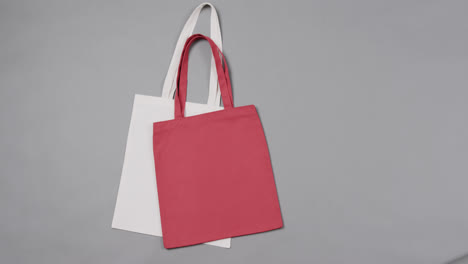 Close-up-of-white-and-red-bags-on-grey-background,-with-copy-space,-slow-motion