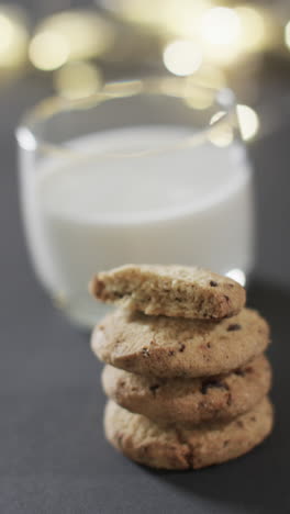 Vertical-video-of-mug-of-milk-and-christmas-cookies-and-copy-space-on-black-background