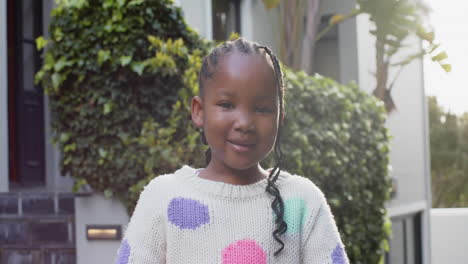 Portrait-of-happy-african-american-girl-with-braided-hair-smiling-in-sunny-garden,-slow-motion