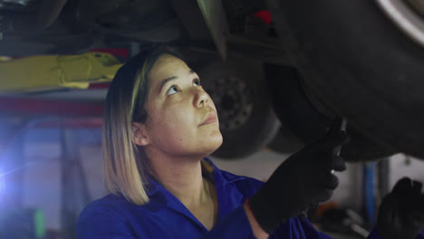 Animación-De-Una-Mecánica-Asiática-Parada-Debajo-De-Un-Auto-Examinando-Un-Vehículo-Con-Una-Herramienta-Manual-En-El-Garaje