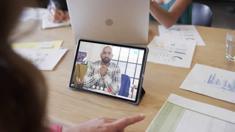 Caucasian-businesswoman-on-tablet-video-call-with-african-american-male-colleague-on-screen