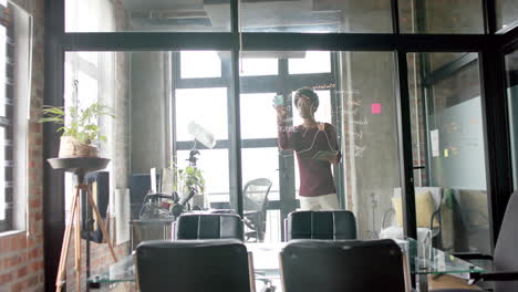 African-american-casual-businessman-using-tablet-writing-on-wall-at-office,-slow-motion,-copy-space