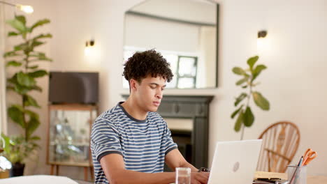 Hombre-Birracial-Trabajando-Desde-Casa-Usando-Una-Computadora-Portátil,-Cámara-Lenta