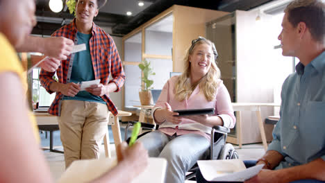 Happy-diverse-male,-female-and-disabled-colleagues-in-discussion-at-casual-office-meeting