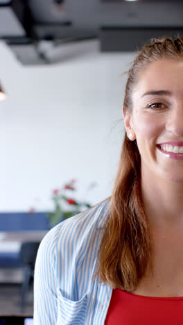 Vertical-video-of-portrait-of-happy-caucasian-businesswoman-in-office-in-slow-motion