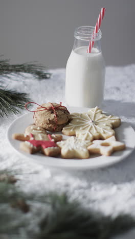 Vertical-video-of-bottle-of-milk,-cookies-with-copy-space-on-snow-background