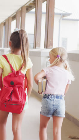 Video-of-back-view-of-diverse-girls-walking-at-school-corridor-and-talking