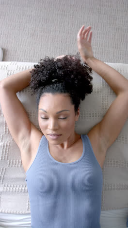 Vertical-video-of-biracial-woman-taking-nap-on-bed-at-home,-slow-motion