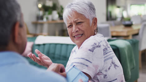 Senior-diverse-couple-talking-and-measuring-blood-pressure