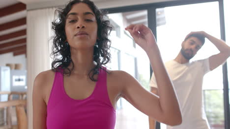 Biracial-couple-doing-yoga-and-stretching-at-home,-in-slow-motion