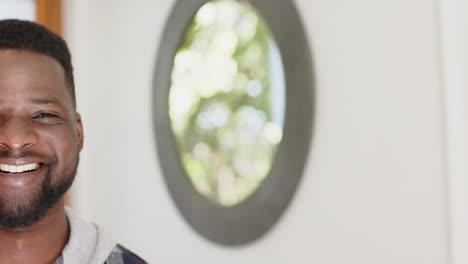 Half-face-of-happy-african-american-man-standing-and-smiling-in-sunny-house