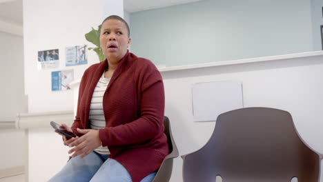 Sad-african-american-woman-in-hospital-waiting-room-and-using-smartphone,-slow-motion,-copy-space