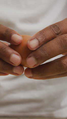 Video-of-close-up-of-biracial-man-cracking-egg-on-white-background