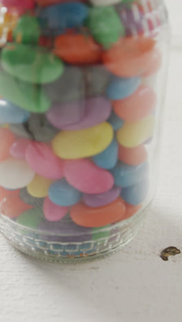 Video-of-multi-coloured-jelly-sweets-in-jar-over-white-rustic-background