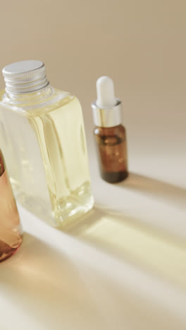 Vertical-video-of-close-up-of-glass-bottles-and-copy-space-on-beige-background