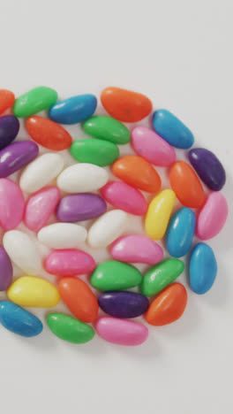 Video-of-overhead-view-of-multi-coloured-sweets-forming-circle-over-white-background